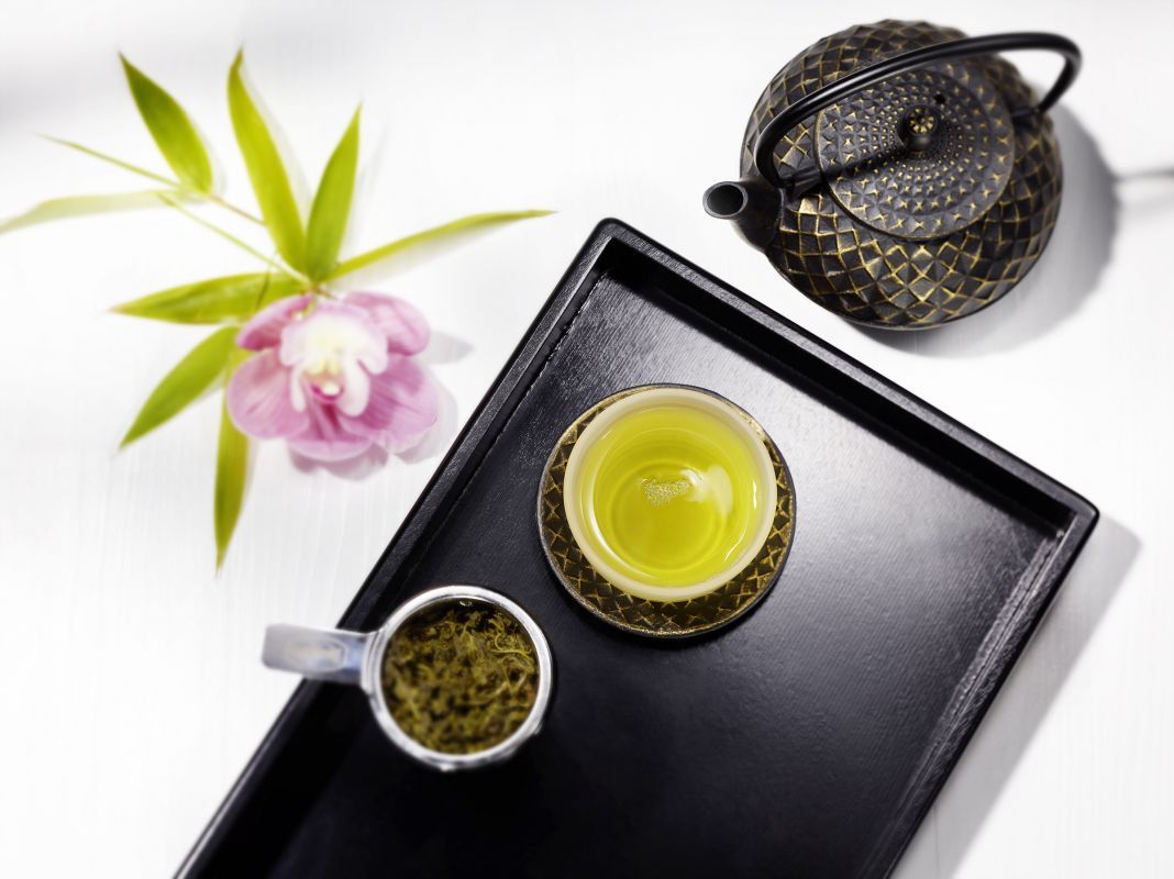 Tablett mit asiatischen Teebechern und gusseiserner Teekanne von oben