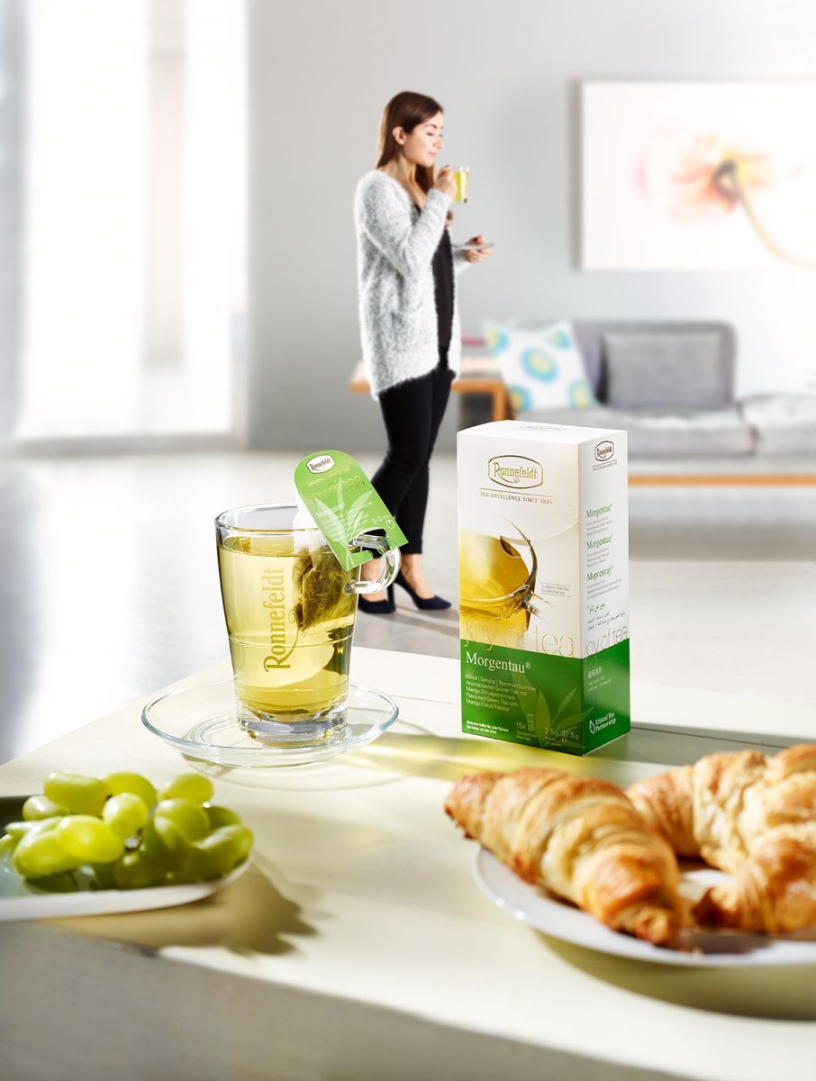 Frühstück mit Ronnefeldt Morgentau Tee, Tee trinkende Frau im Hintergrund