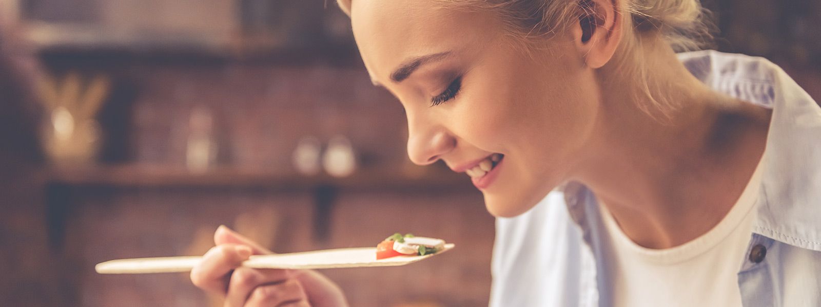 Frau kostet Essen auf einem Kochlöffel