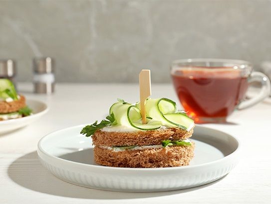 Rundes Gurkensandwich mit Teetasse im Hintergrund