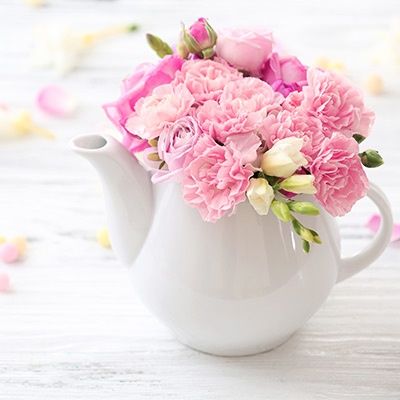 Rosa Blumen in weißer Porzellankanne