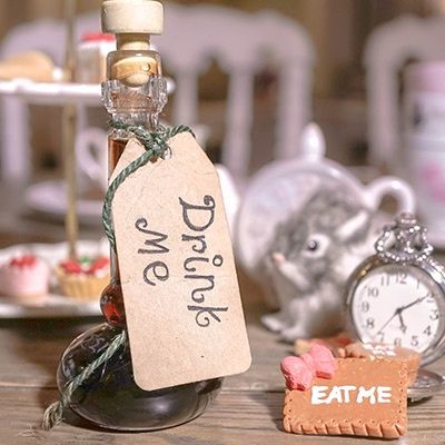Fläschchen mit Drink Me-Aufschrift, daneben Eat me-Keks