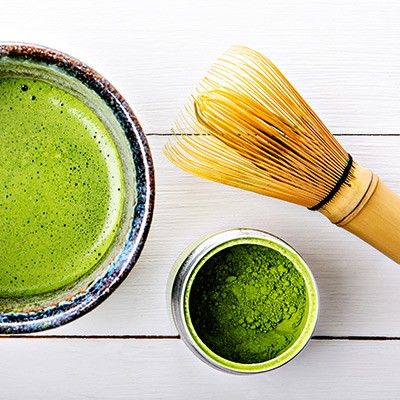 becher mit Matcha-Tee und Matcha-Besen