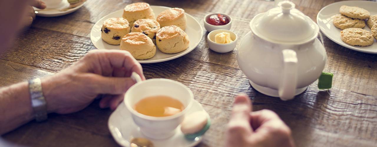 Teekanne, -tasse und Scones auf Tisch