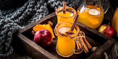 Gläser mit winterlichen Tee-Drinks mit Zimt, Orange und Apfel
