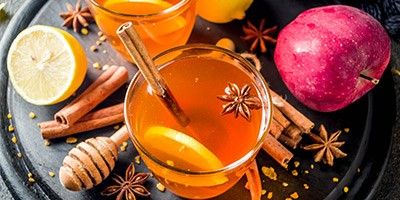 Tasse mit Tee, darum herum Dekoration aus winterlichen Gewürzen und Früchten