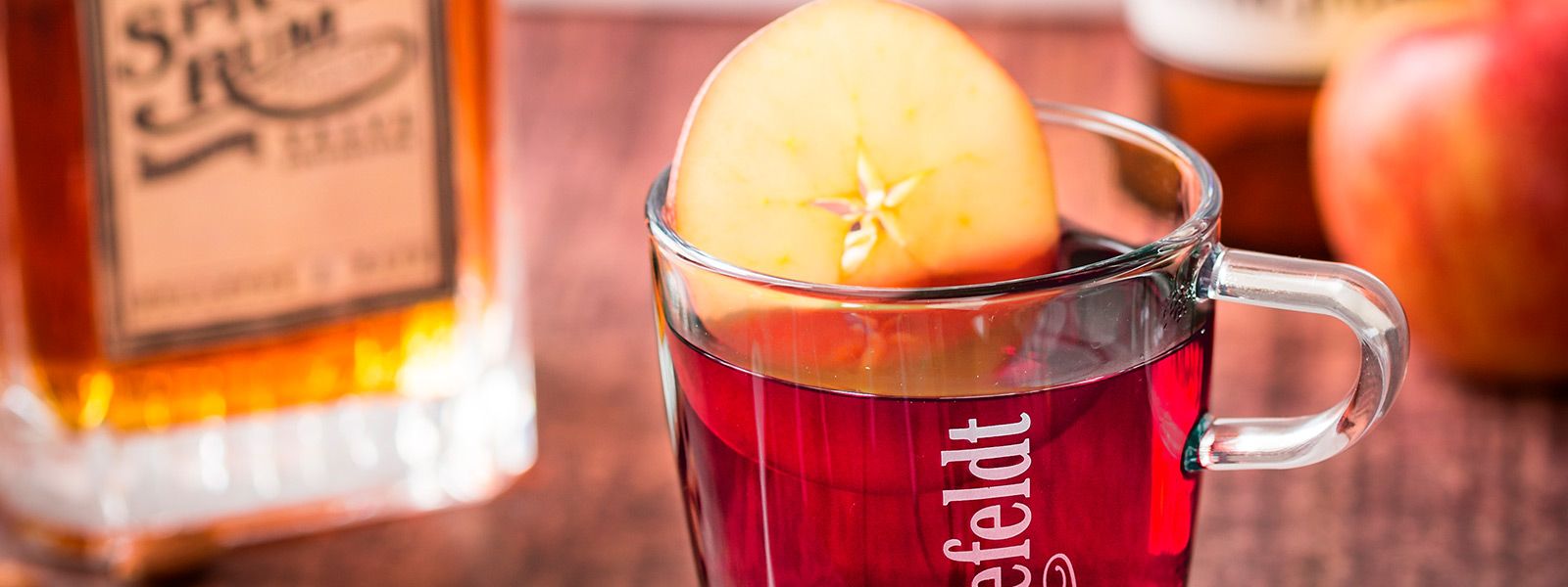 Teetasse mit Orangenscheibe und Rum im Hintergrund