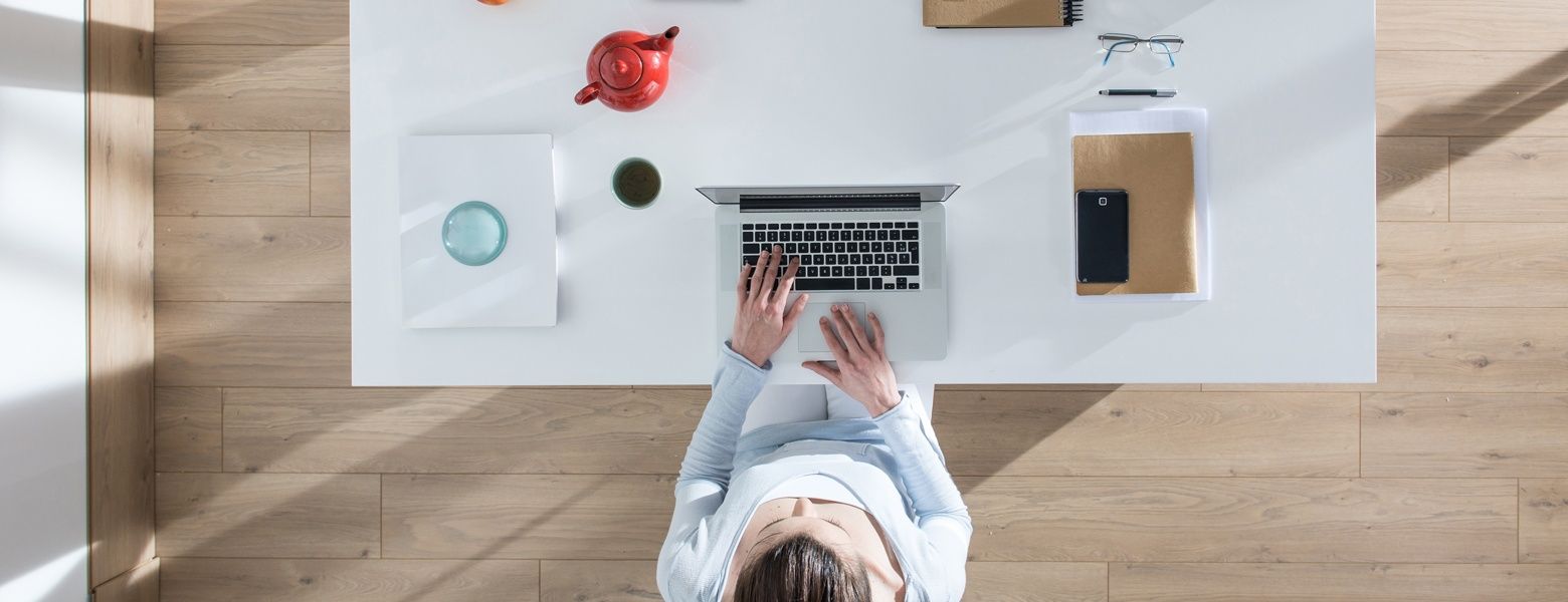 Arbeiten mit Ronnefeldt Draufsicht auf einen Schreibtisch mit Laptop, Notizbuch und Teekanne